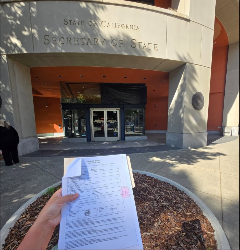 A California Secretary of State Apostille certificate held in front of the Secretary of State building